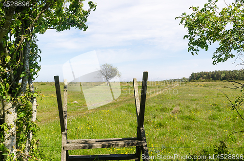 Image of Wooden stile by a green and bright pastureland by spring season