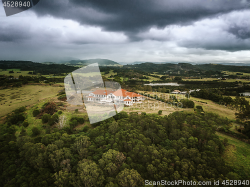 Image of Storm clouds loom over abandoned mansion in rural setting