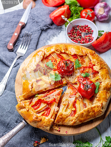 Image of Open pie with potatoes, bacon and tomatoes.