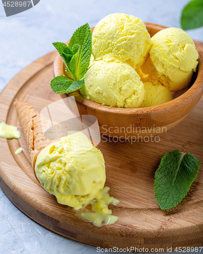 Image of Golden colored turmeric ice cream in wooden bowl.