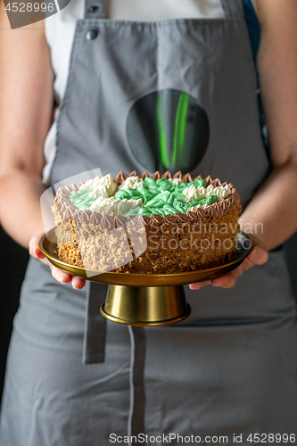 Image of Women\'s hands holding a birthday cake.