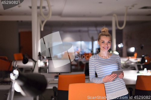 Image of woman working on digital tablet in night office