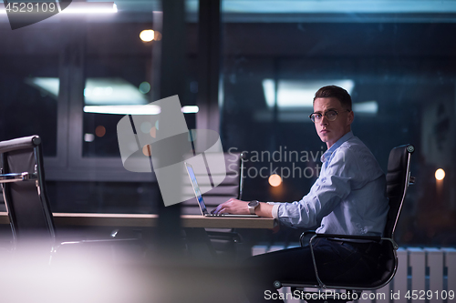 Image of man working on laptop in dark office