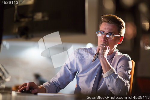 Image of man working on computer in dark office