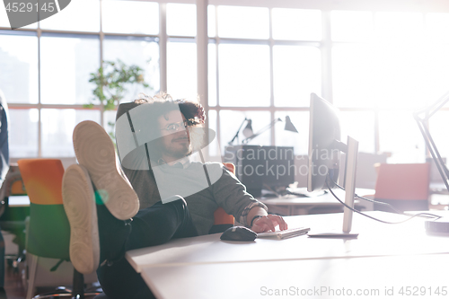 Image of businessman sitting with legs on desk