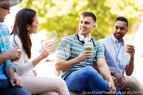 Image of friends drinking coffee and juice talking in city