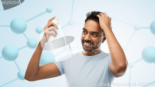 Image of smiling indian man applying hair spray