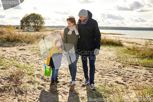 Image of happy family walking along autumn beach