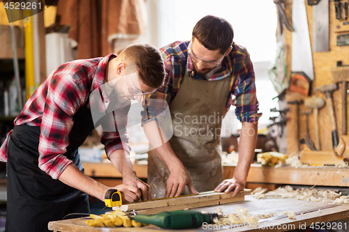 Image of carpenters with ruler and wooden board at workshop