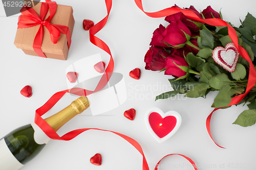 Image of close up of champagne, gift, candies and red roses