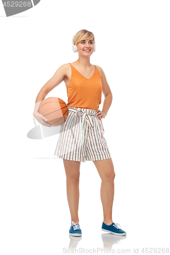 Image of smiling teenage girl in headphones with basketball