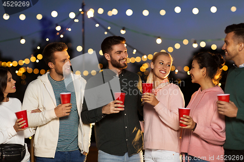 Image of friends with party cups on rooftop at night