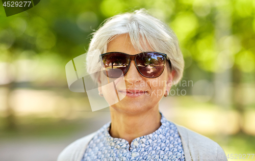 Image of portrait of happy senior woman at summer park