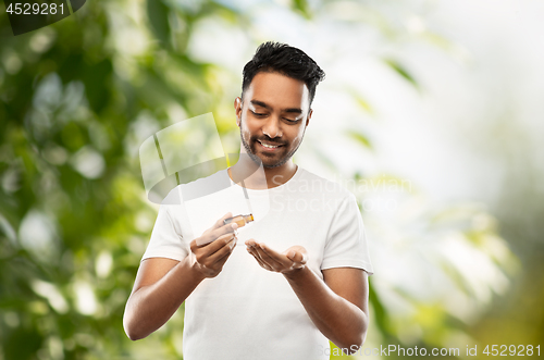 Image of indian man applying grooming oil to his hand