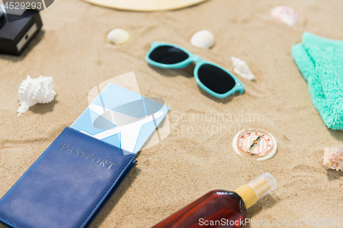 Image of travel tickets, camera and hat on beach sand