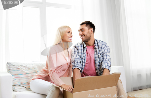 Image of happy couple with open parcel box at home