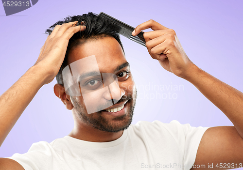 Image of happy indian man brushing hair with comb