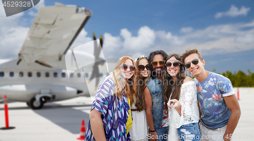 Image of friends taking picture by selfie stick on airfield