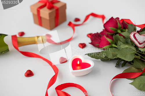 Image of close up of champagne, gift, candies and red roses