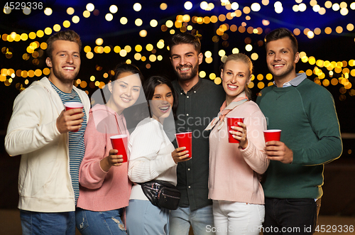 Image of friends with party cups on rooftop at night