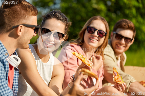 Image of friends eating pizza at picnic in summer park