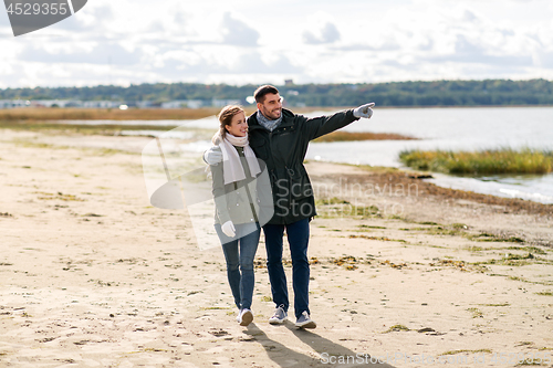 Image of couple walking along autumn beach