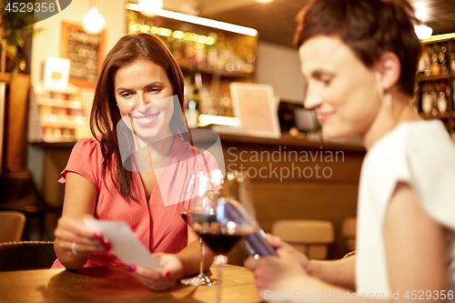 Image of women looking at bill at wine bar or restaurant