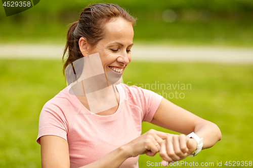 Image of woman with smart watch or fitness tracker in park