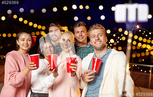 Image of friends with drinks taking selfie at rooftop party