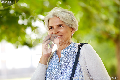 Image of senior woman calling on smartphone in summer park