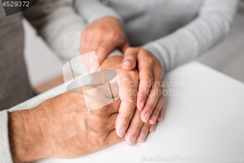 Image of close up of young woman holding senior man hands