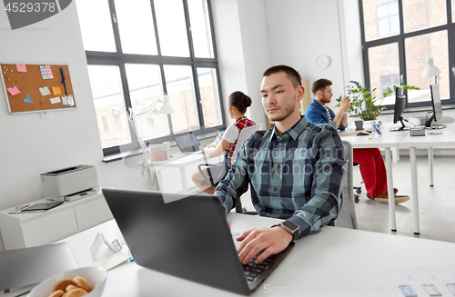 Image of creative man with laptop working at office