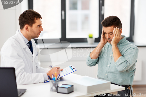 Image of doctor and male patient having headache at clinic