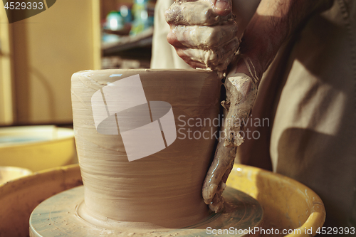 Image of Creating a jar or vase of white clay close-up. Master crock.