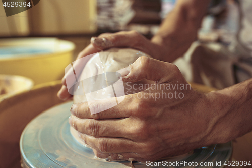 Image of Creating a jar or vase of white clay close-up. Master crock.