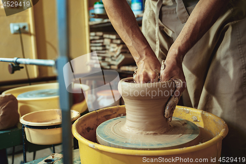 Image of Creating a jar or vase of white clay close-up. Master crock. Man hands making clay jug macro.