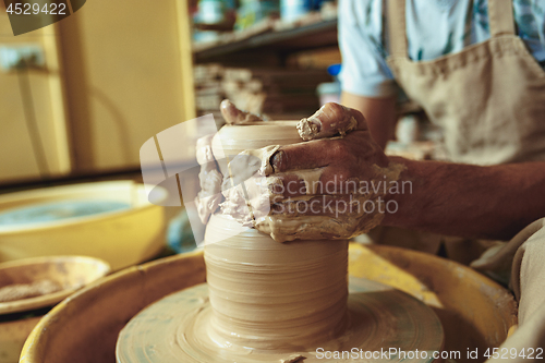 Image of Creating a jar or vase of white clay close-up. Master crock. Man hands making clay jug macro.