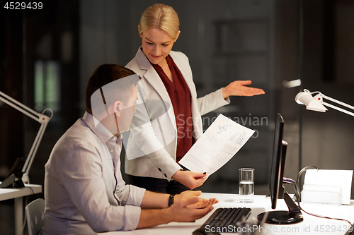 Image of business team with papers working late at office