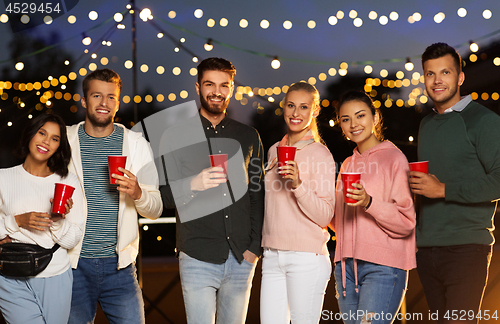 Image of friends with party cups on rooftop at night