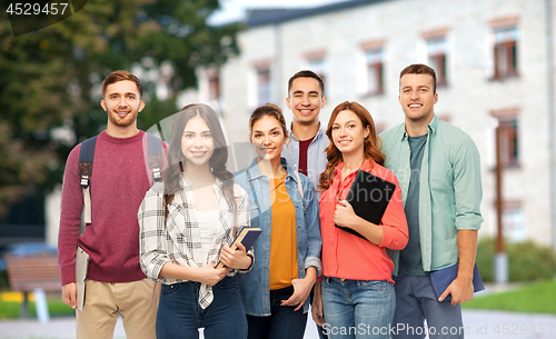 Image of group of smiling students with books over campus