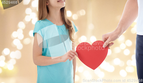 Image of close up of girl and father hand holding red heart