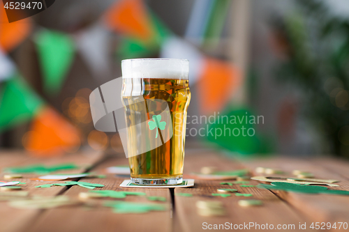 Image of glass of beer with shamrock and coins on table