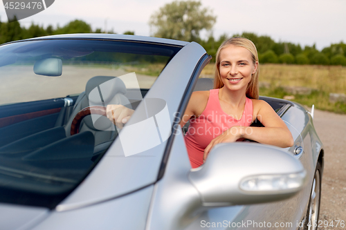 Image of happy young woman driving convertible car