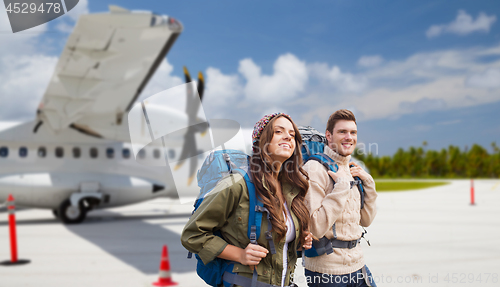 Image of couple of tourists with backpacks over plane