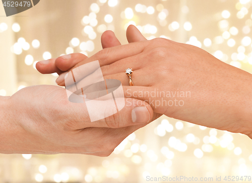 Image of close up of couple hands with engagement ring