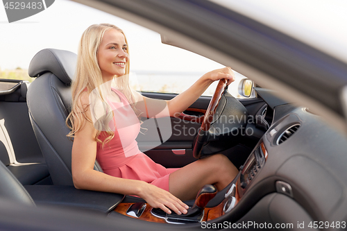 Image of happy young woman in convertible car