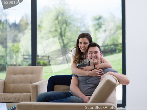 Image of young handsome couple hugging on the sofa