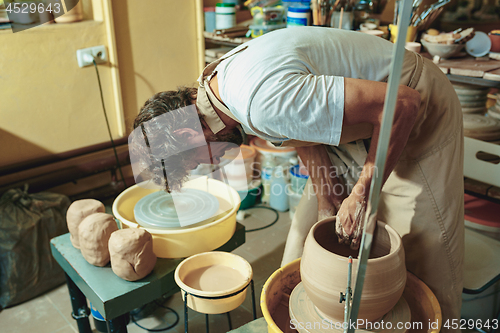 Image of Creating a jar or vase of white clay close-up. Master crock.