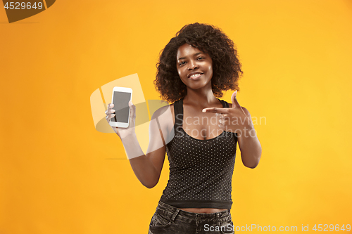 Image of Portrait of a confident casual afro girl showing blank screen mobile phone