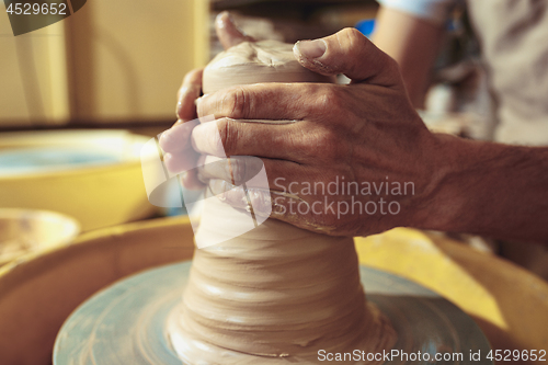 Image of Creating a jar or vase of white clay close-up. Master crock.